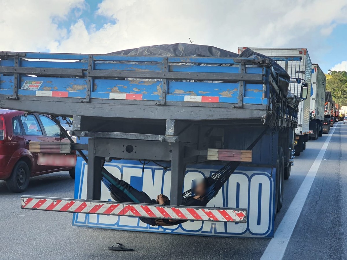 Caminhoneiro 'descansa' em rede improvisada durante congestionamento causado por veículo em chamas